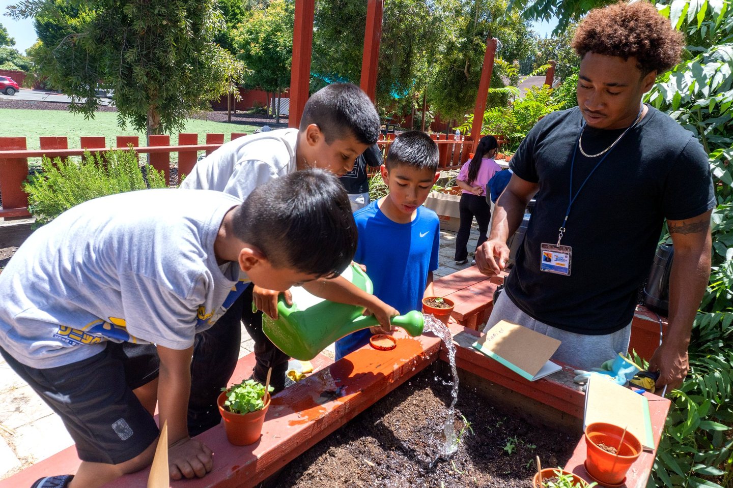 Hope Horizon students watering a raised garden bed with a staff member